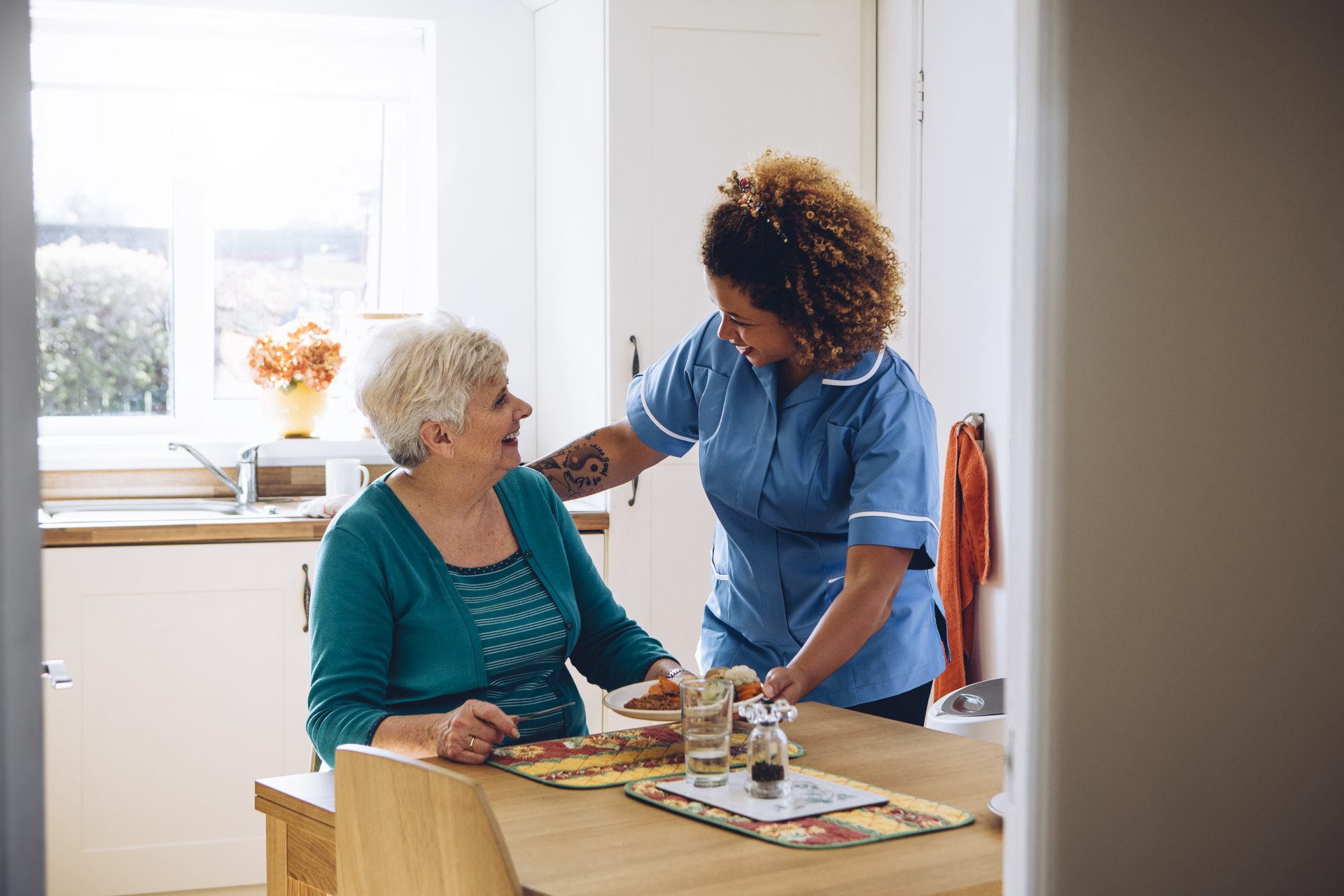 Young care nurse on home visit comforting senior woman